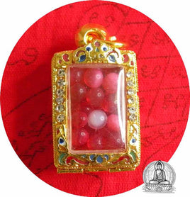 Perles reliques Sarira rouges dans un reliquaire doré.